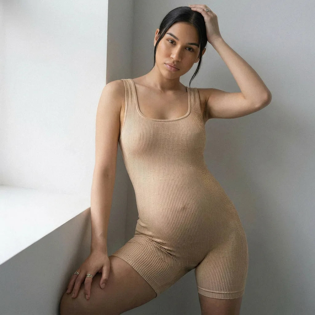 Nude maternity seamless bodysuit scoop neck ribbed silhouette, leaning fashion editorial