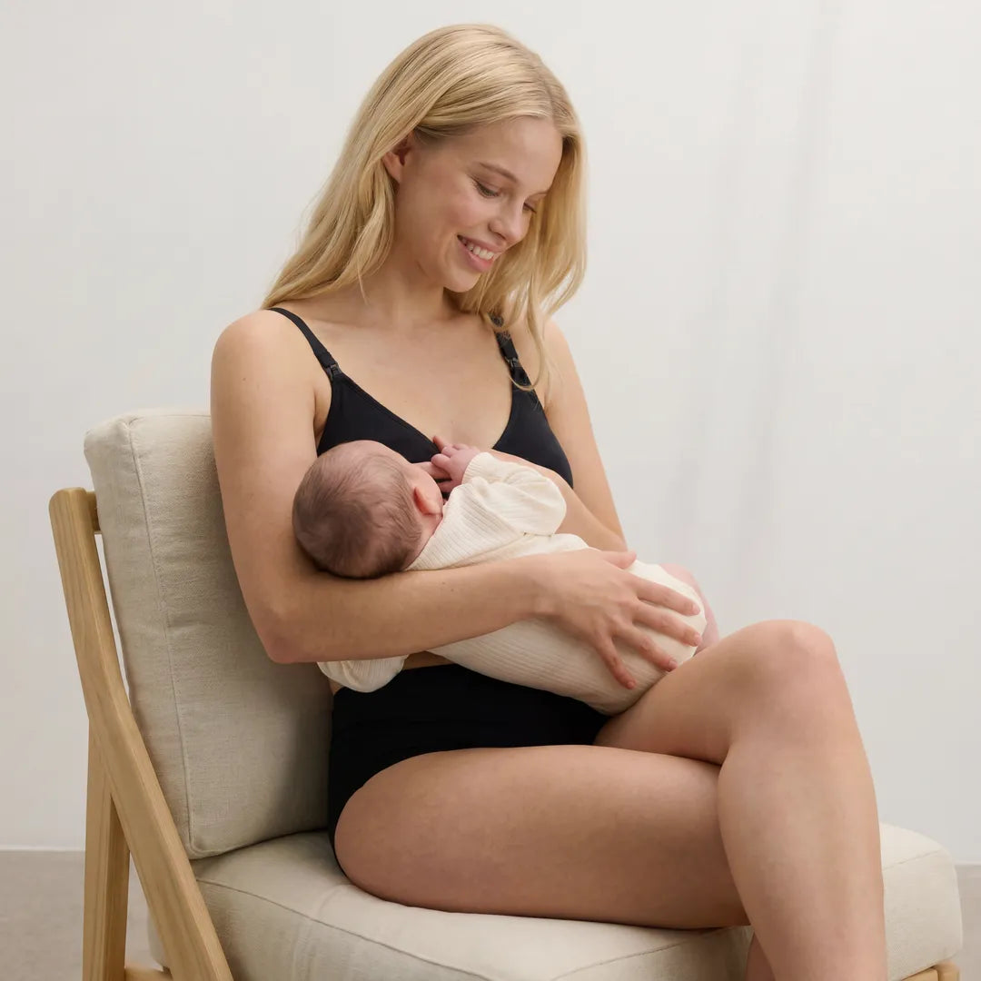 Black classic nursing bra drop-cup strap clip nursing access, lifestyle seated postpartum holding newborn shot