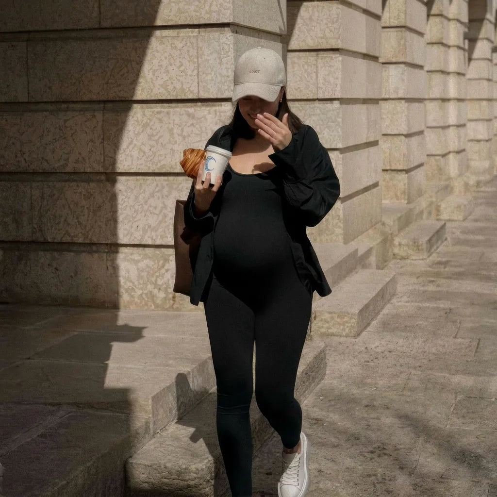 Black maternity daily jumpsuit fitted bump silhouette, outdoor street styled lifestyle