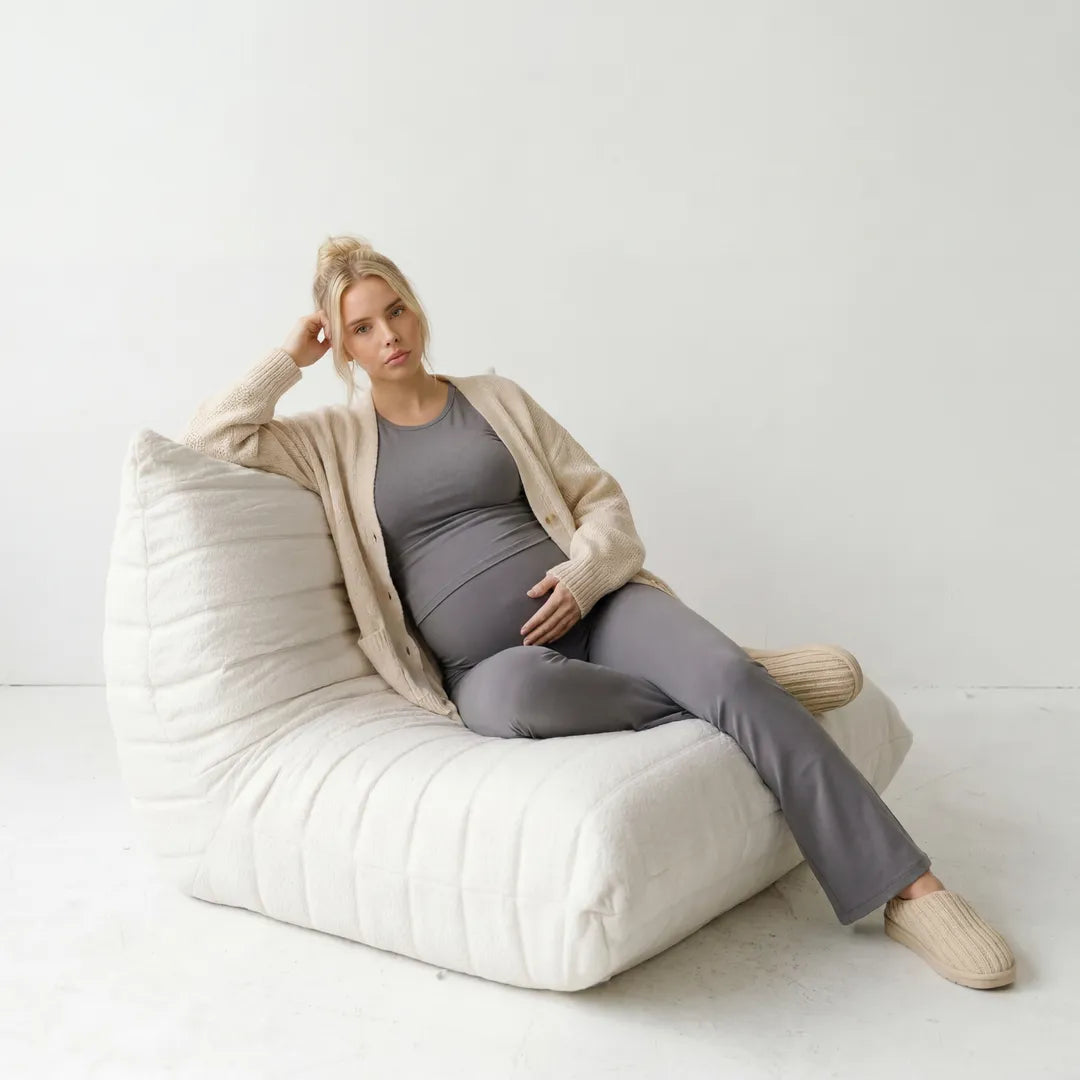 Gray maternity flare leggings worn with cardigan, seated lifestyle shot
