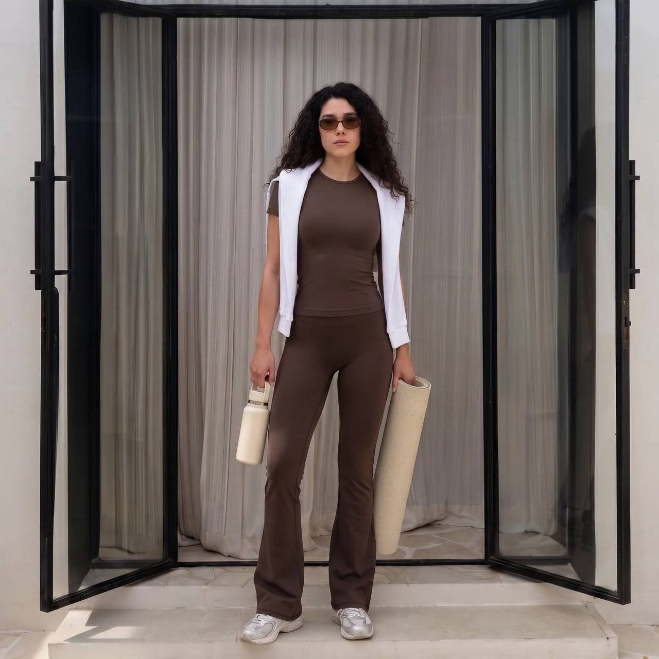 Woman wearing chocolate brown Florecer high-waisted flare legging styled with a white top