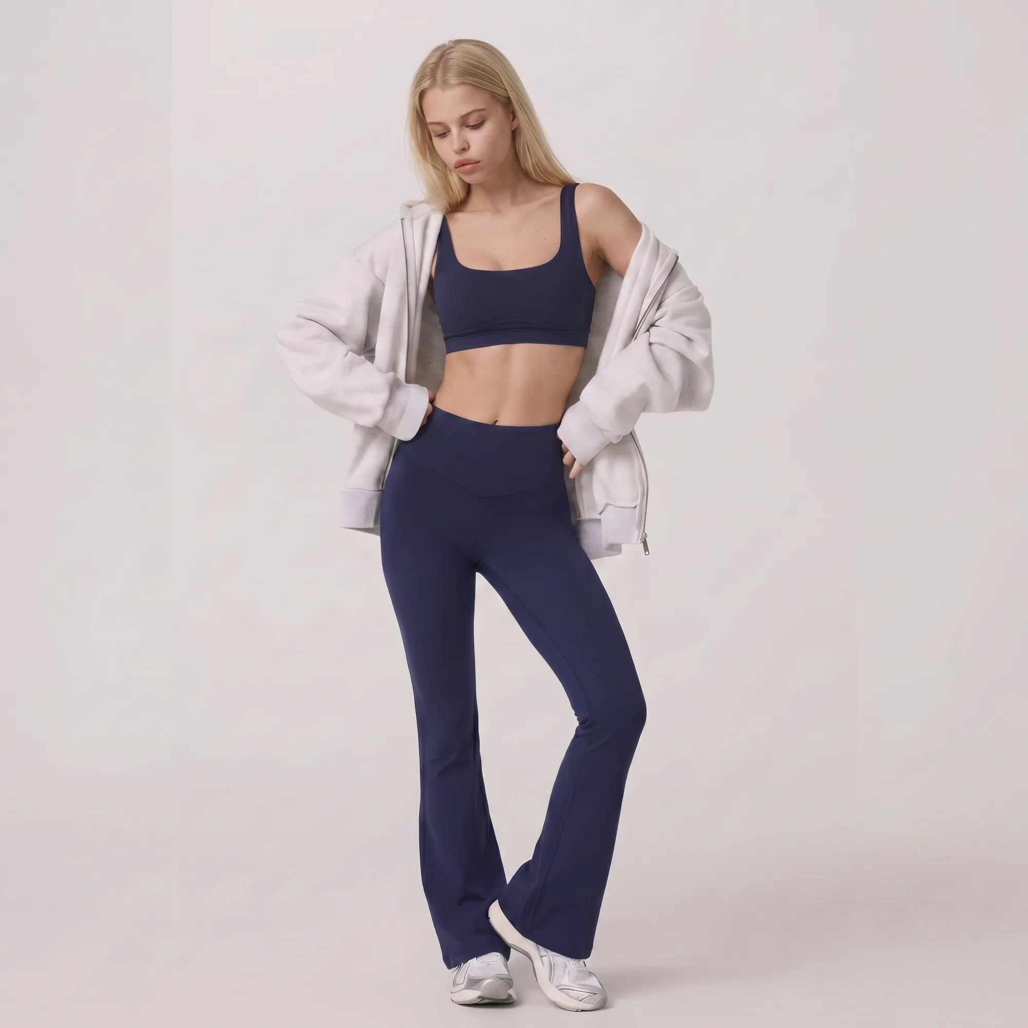 Woman wearing navy Florecer high-waisted flare legging styled with a jacket