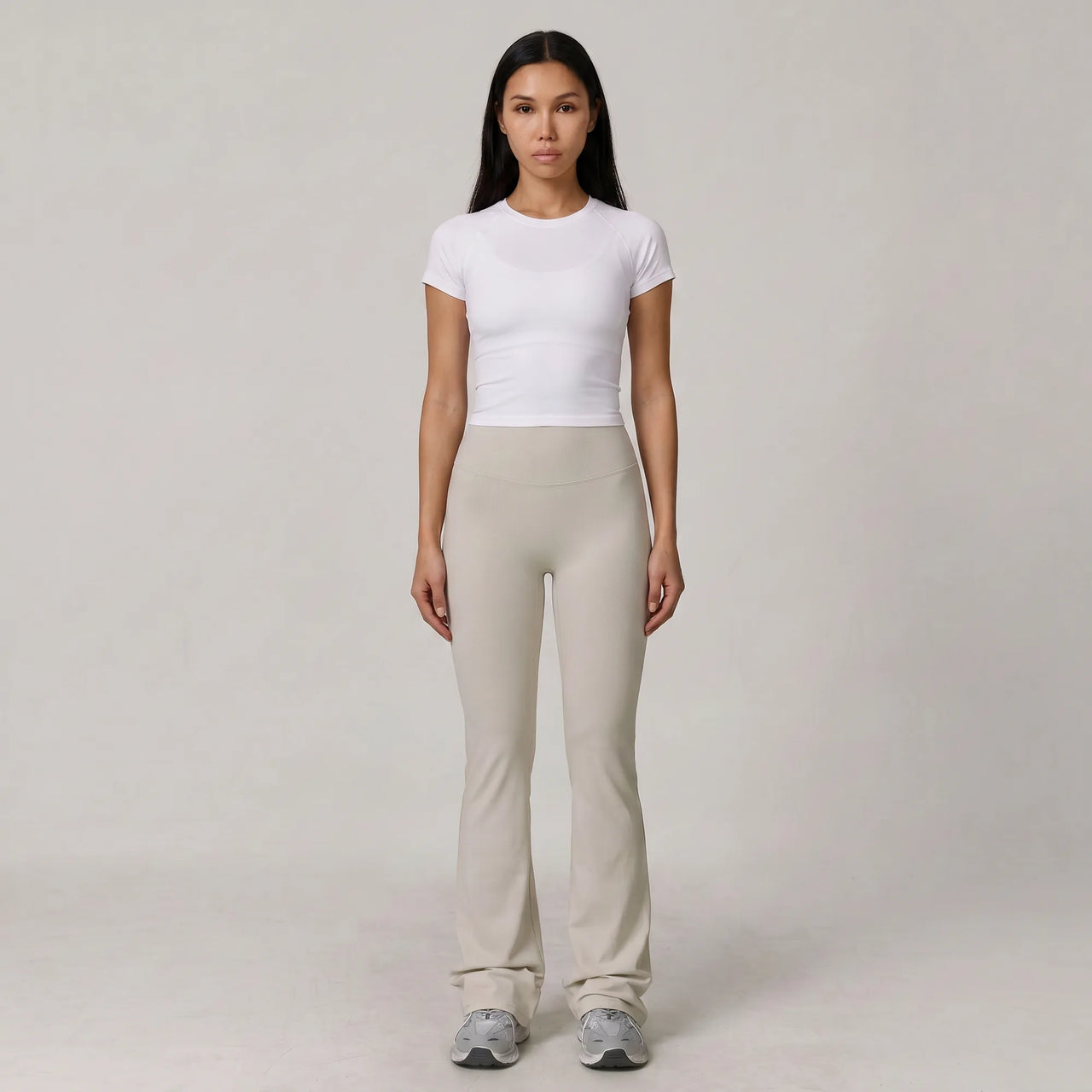 Woman wearing stone Florecer high-waisted flare legging with a white top, front view