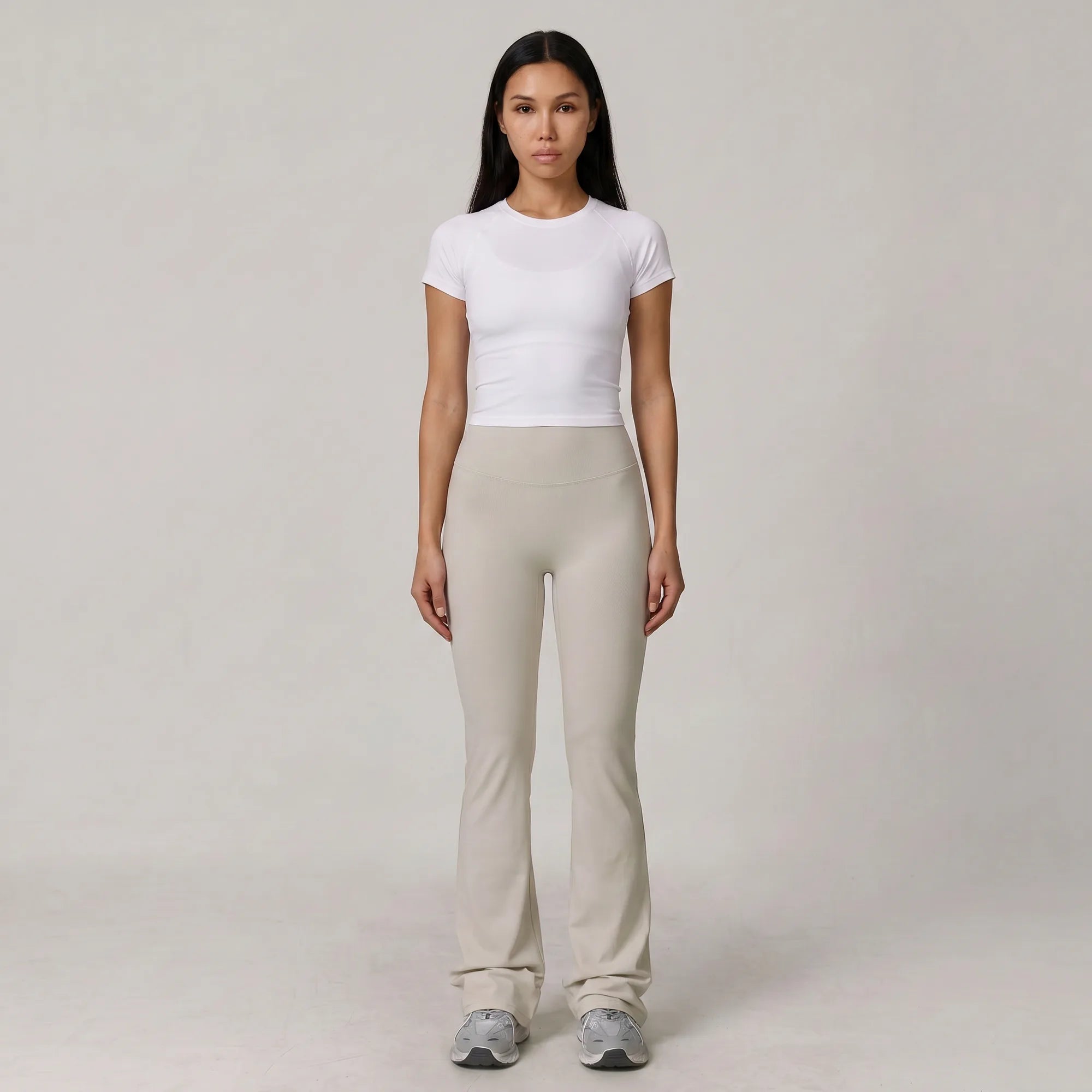 Woman wearing stone Florecer high-waisted flare legging with a white top, front view