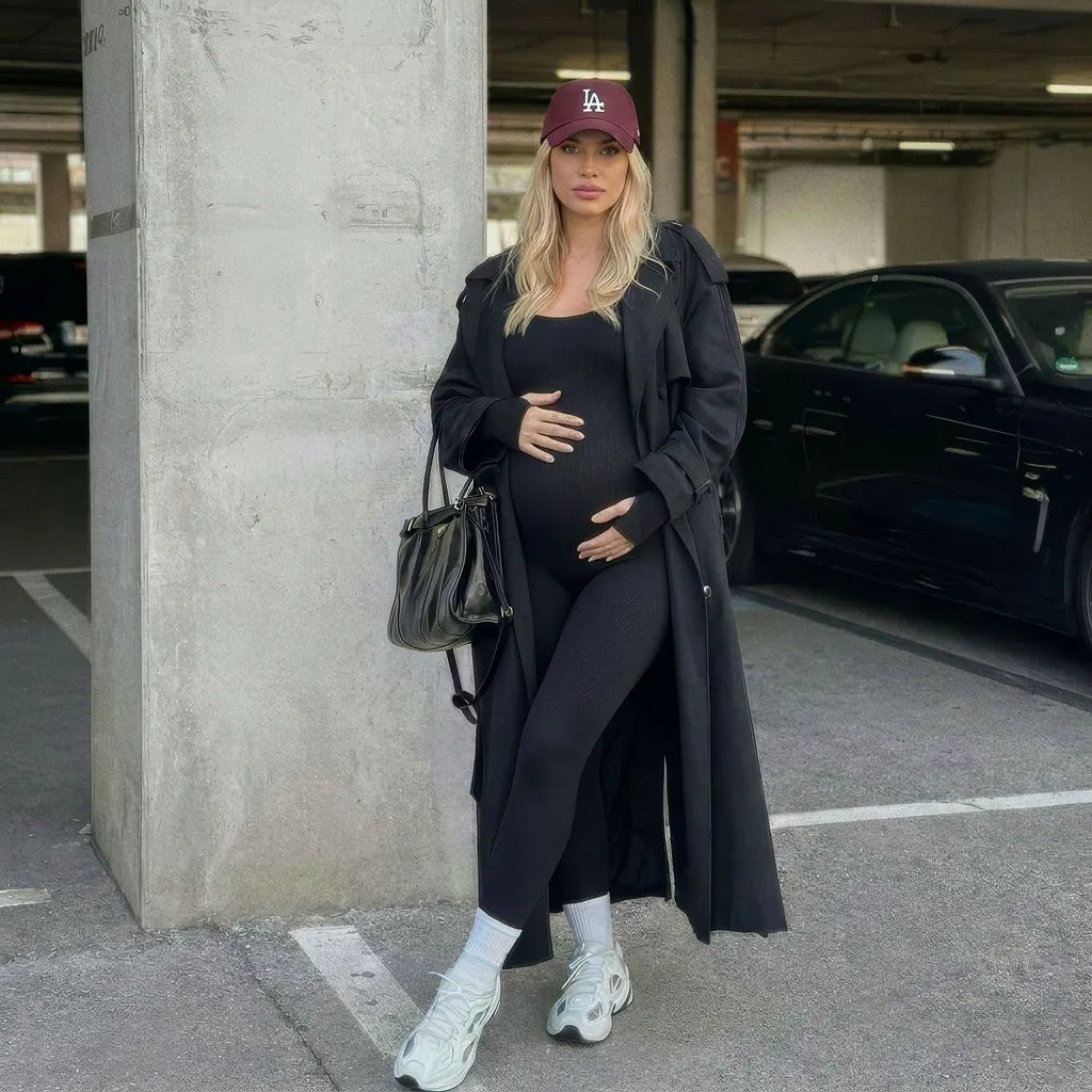 Black maternity jumpsuit styled with long coat and accessories, outdoor urban lifestyle