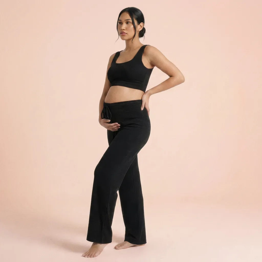 Black knit maternity trousers with matching top, peach background lifestyle