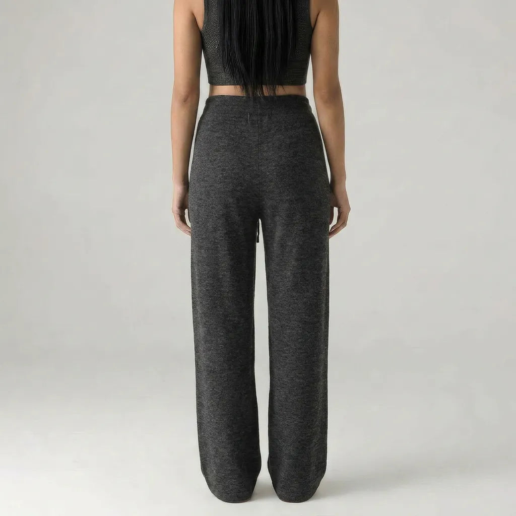 Person wearing dark gray high-waisted pants on a light gray background