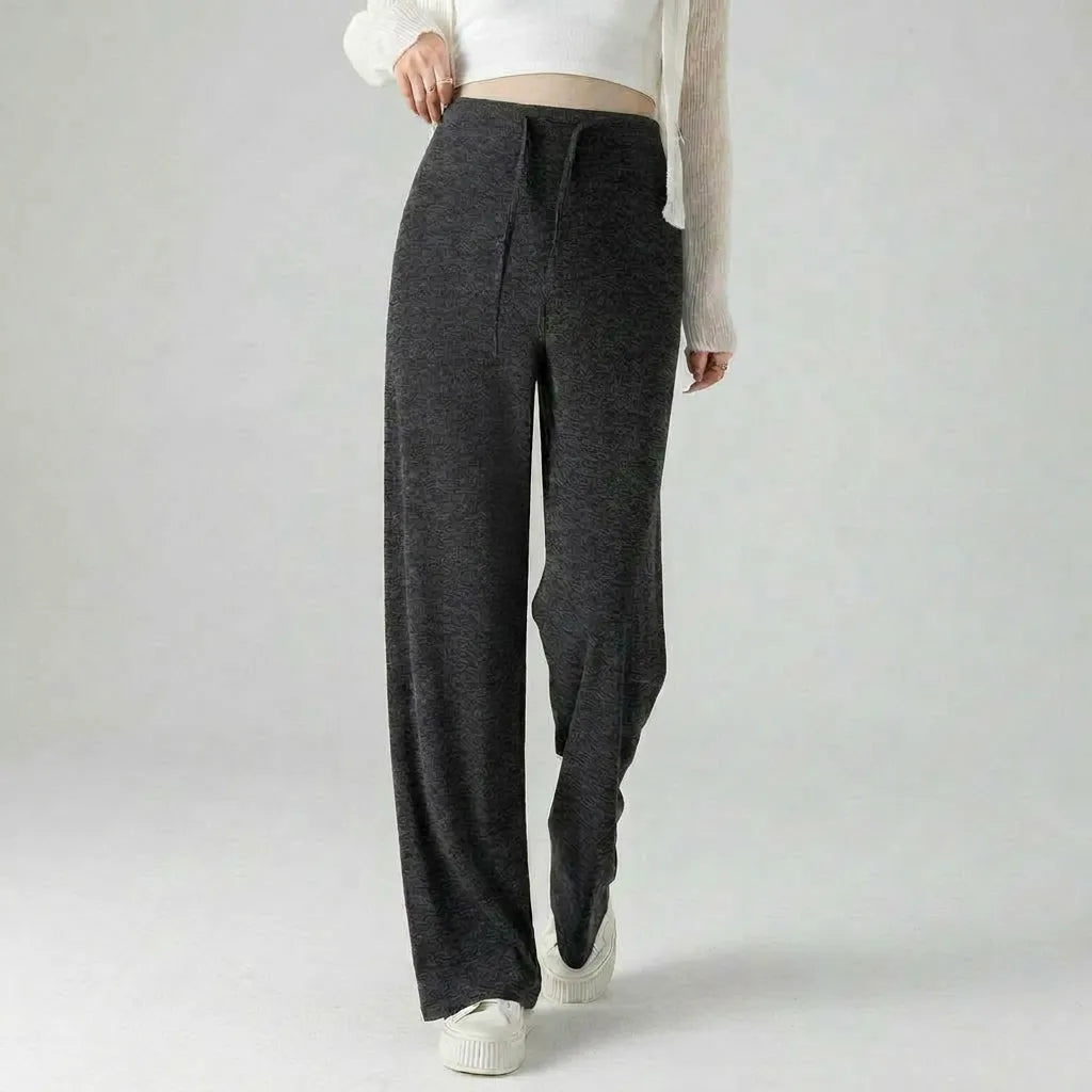 Person wearing dark gray sweatpants on a plain background