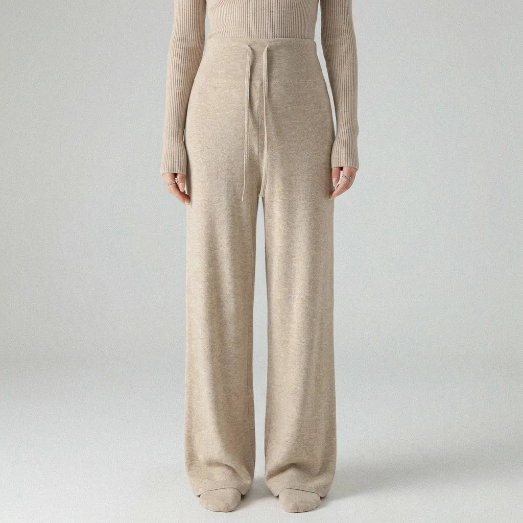 Person wearing a beige knit sweater and pants on a light gray background