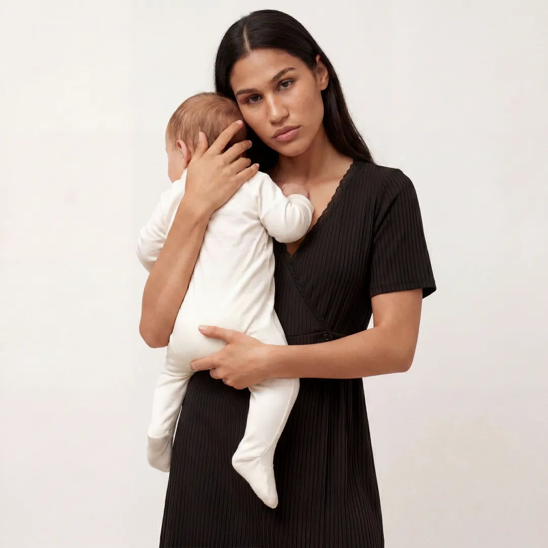 Black postpartum night nursing dress wrap lace trim neckline, half body holding newborn shot