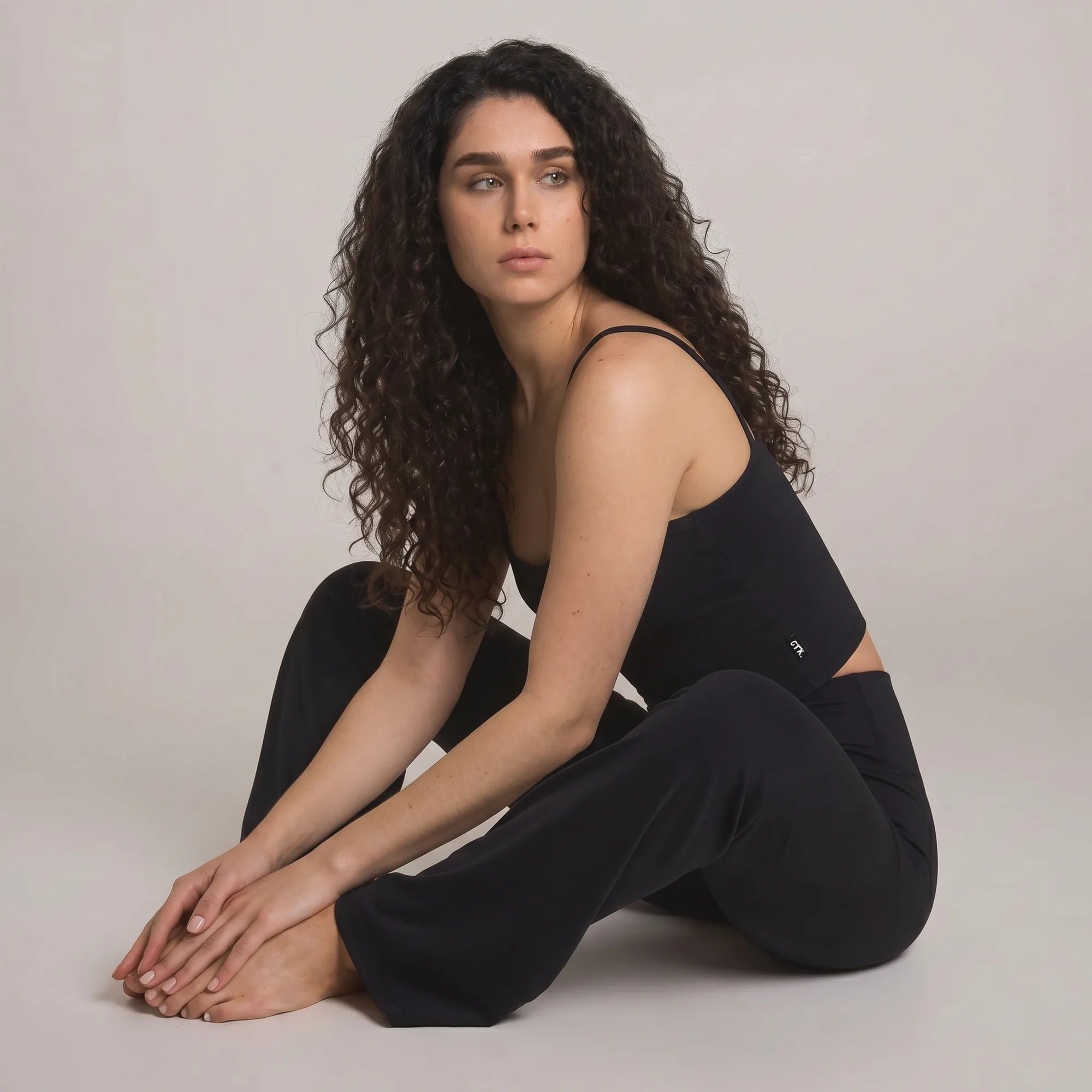  Woman wearing black Pulso high-waisted wide-leg postpartum trouser, seated