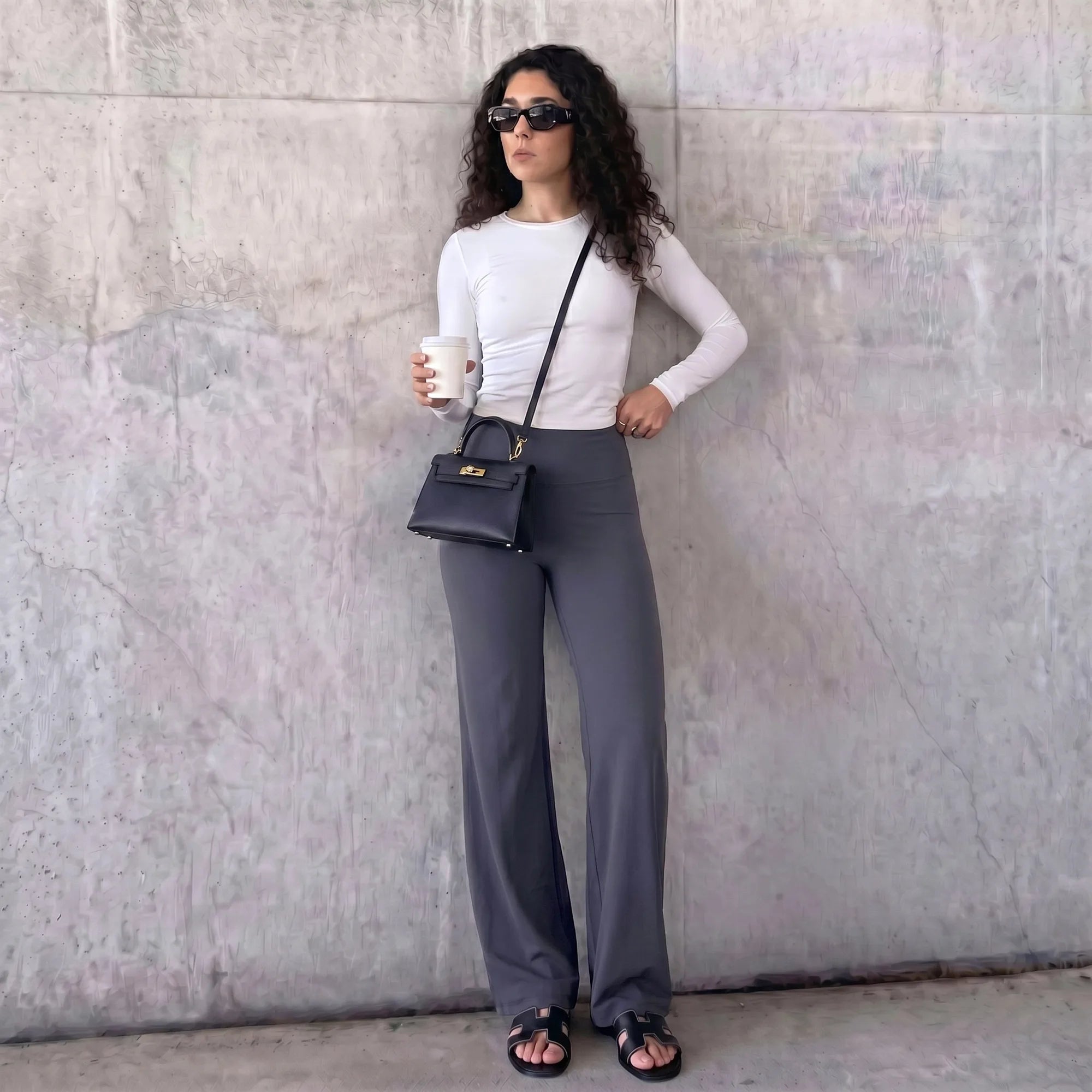 Woman wearing grey Pulso high-waisted wide-leg postpartum trouser styled with a white top, standing outdoors