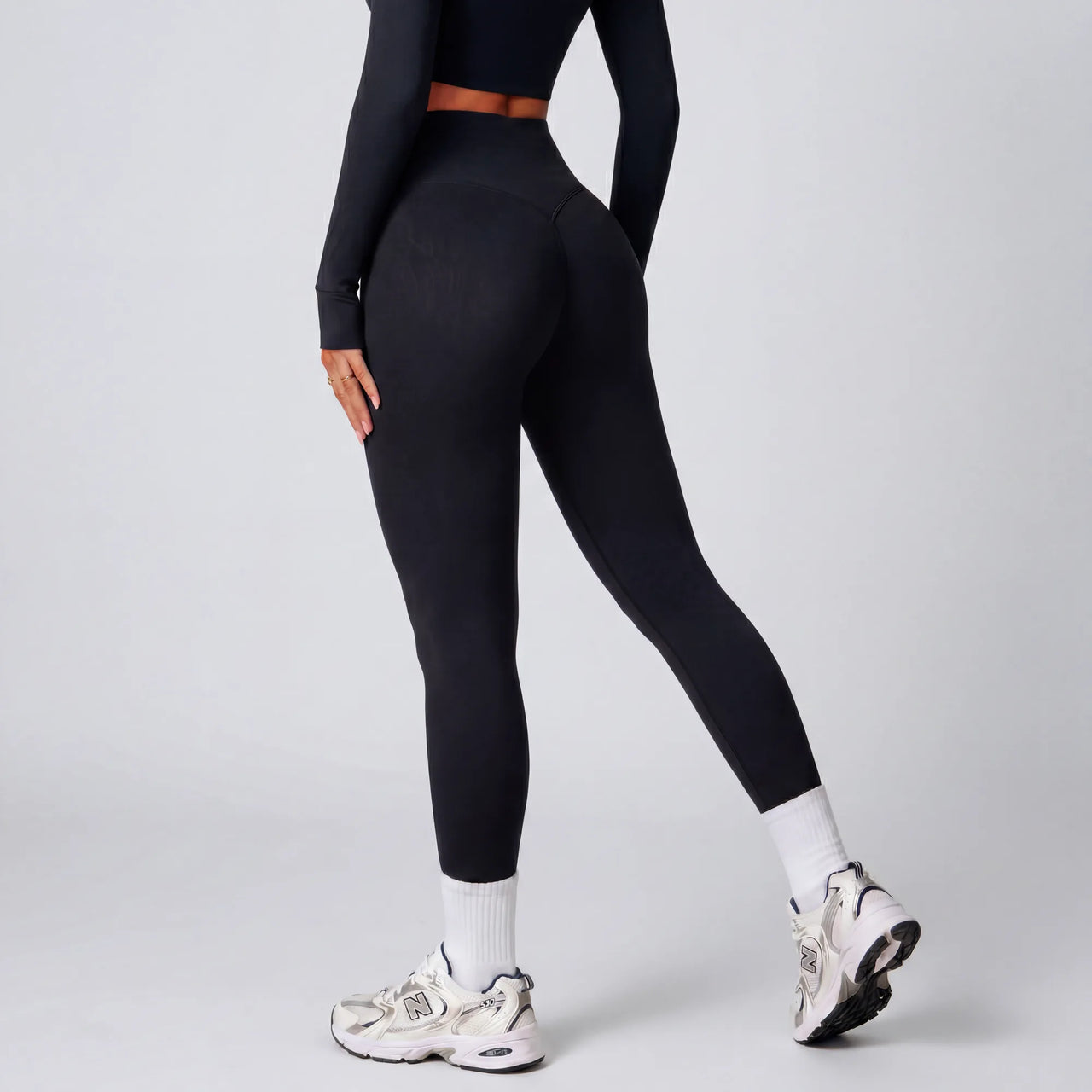 Woman wearing black Retorno high-waisted postpartum legging, back view walking