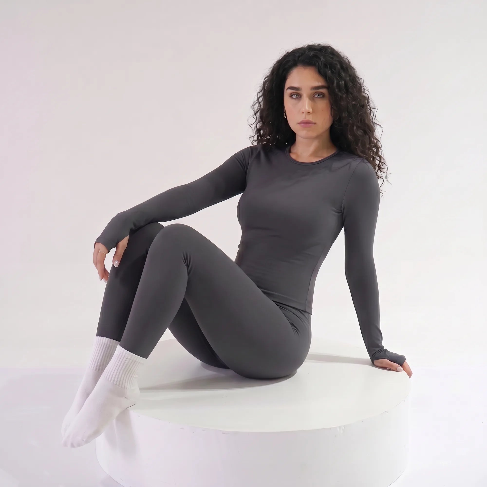 Woman wearing grey Retorno high-waisted postpartum legging, seated relaxed