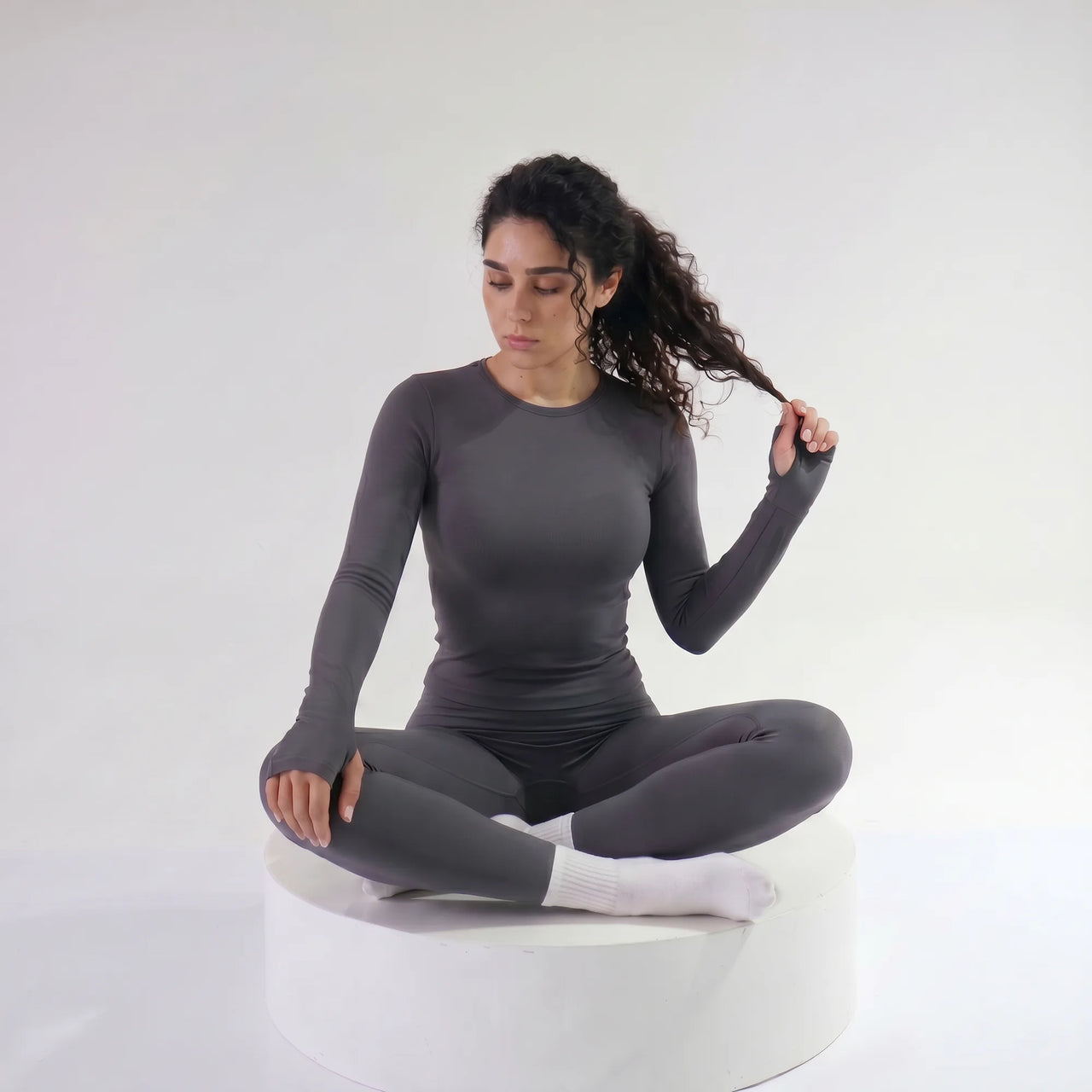 Woman wearing grey Retorno high-waisted postpartum legging, seated