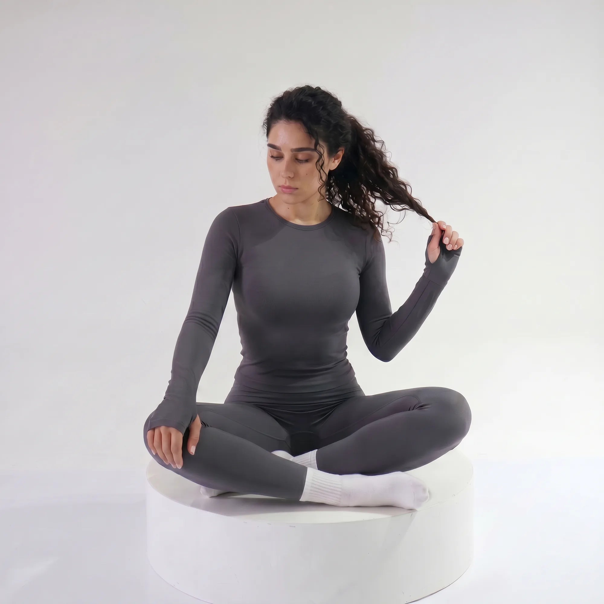 Woman wearing grey Retorno high-waisted postpartum legging, seated