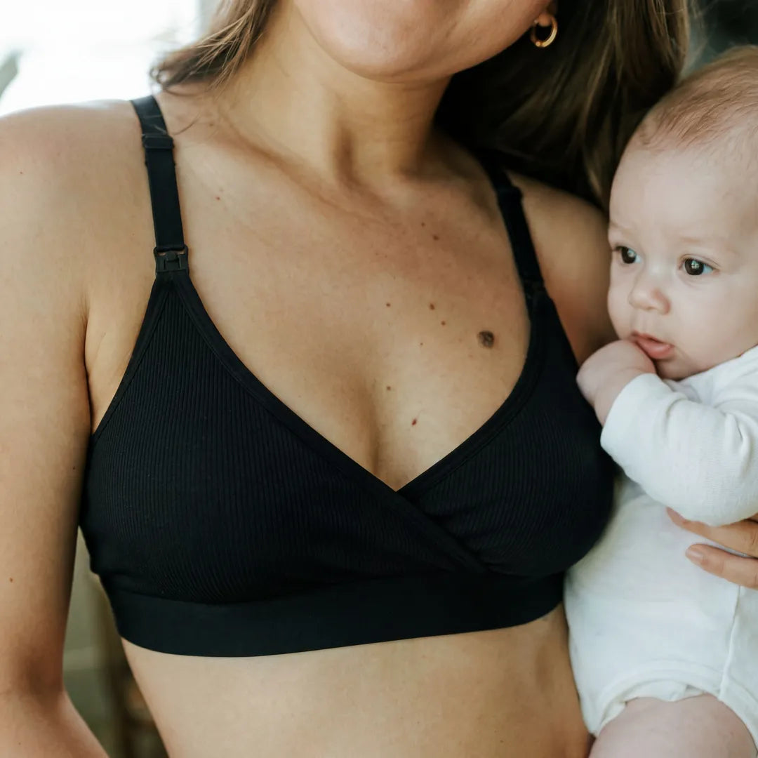 Black seamless nursing bra adjustable strap with clip nursing access, lifestyle postpartum holding newborn shot