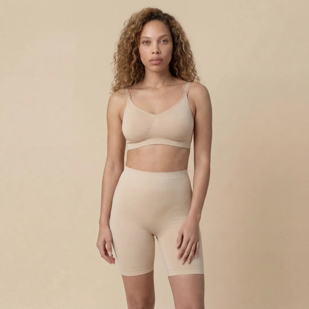 Woman wearing a beige shapewear set against a beige background