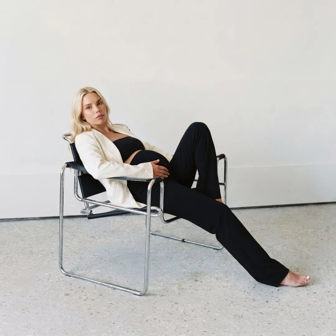 Black seamless yoga trousers styled with white blazer, reclined lifestyle shot